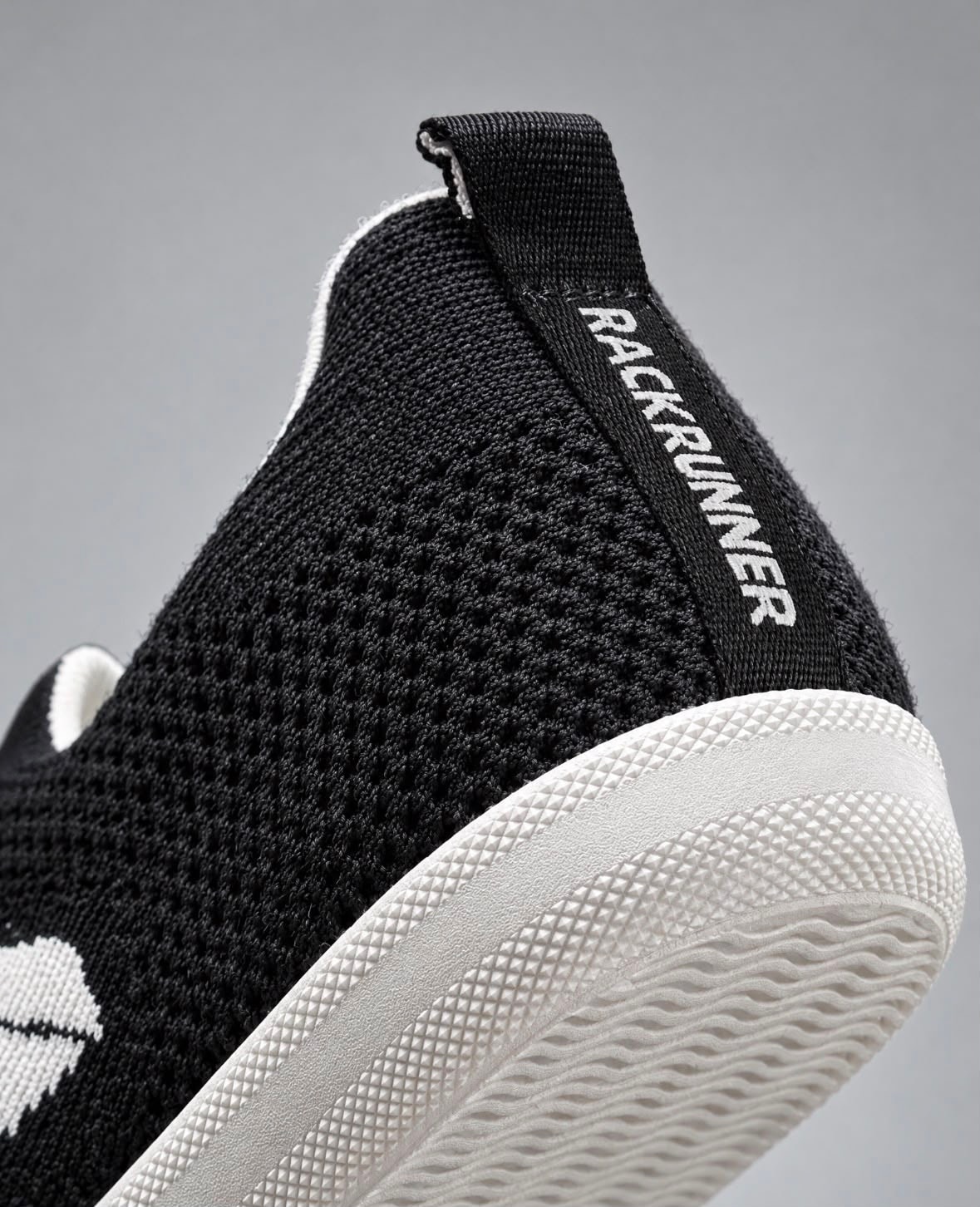Close-up of the Rack Runner heel: the knit, the RACK RUNNER strap and the textured white outsole