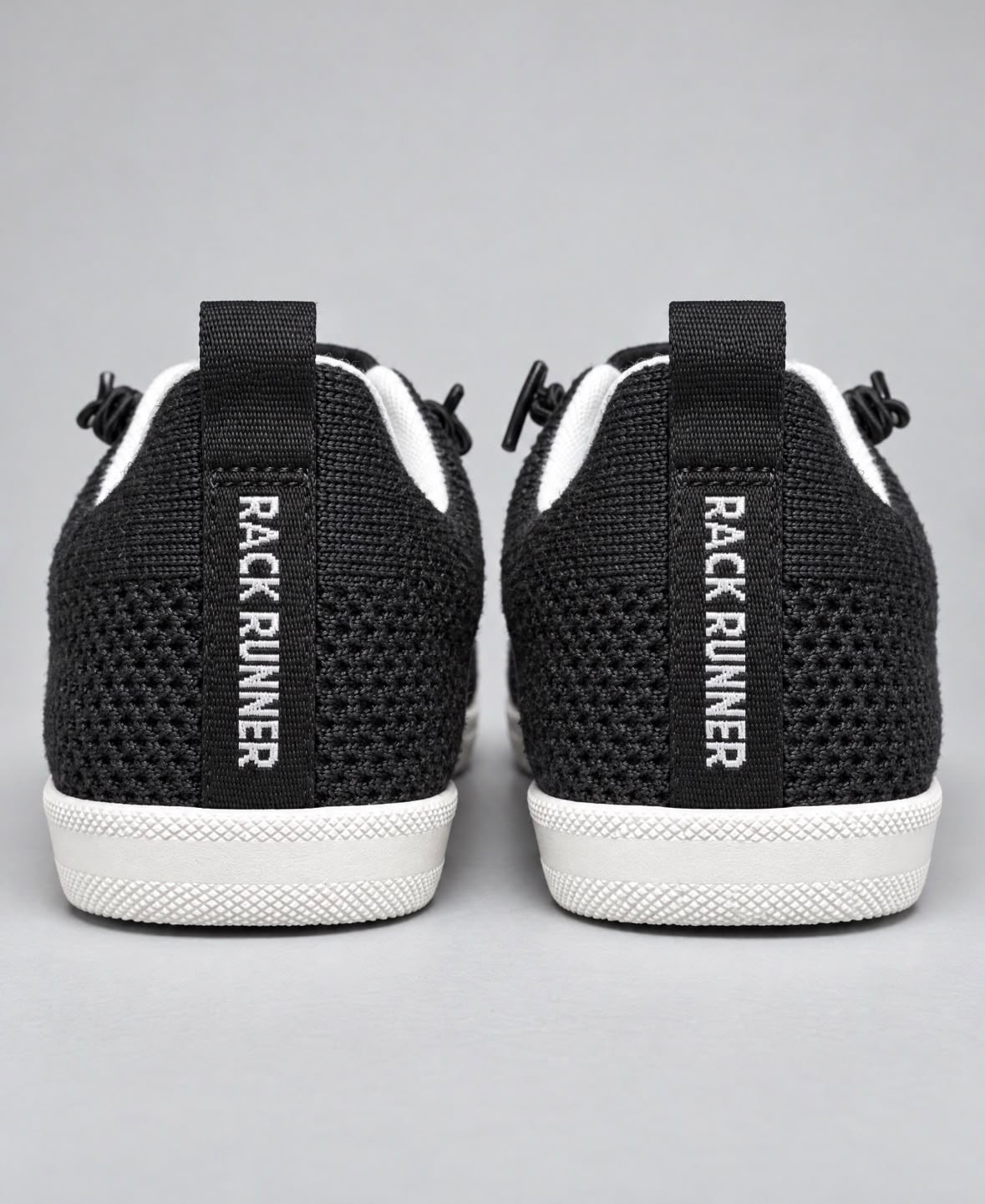 The heels of a pair of Rack Runner shoes, RACK RUNNER in white on each heel strap